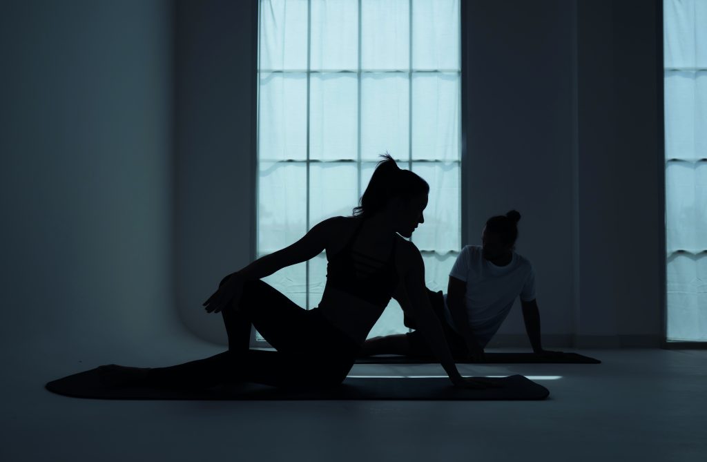 Silhouette of a young couple practicing yoga in the room.