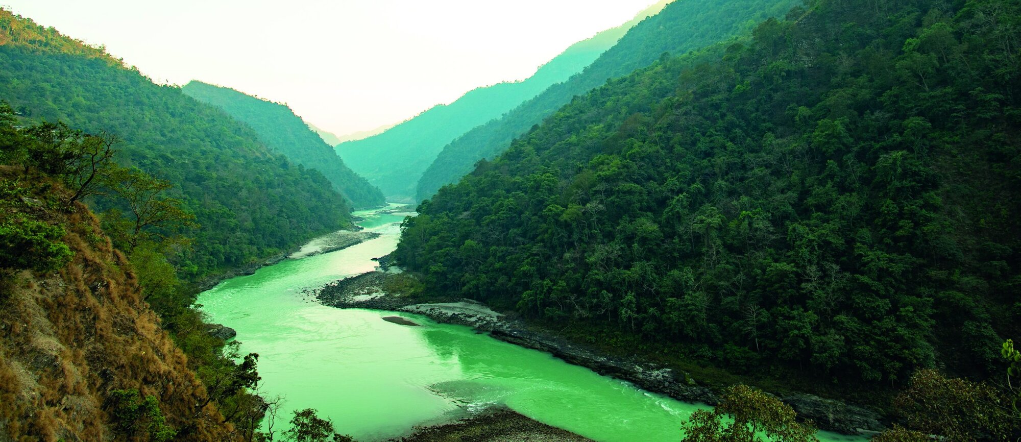 Spectacular view of the sacred Ganges river flowing through the green mountains of Rishikesh, Uttarakhand, India.