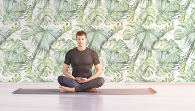 Man sitting at lotus yoga pose. Home morning routine. Teacher fitness studio. Asana class. Online exercise. Relaxation indoor. Male prayer in house room. Light background. Close eyes