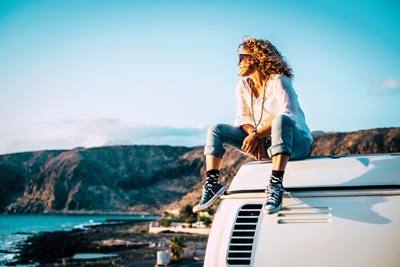 Travel concept with independent people enjoyig the outdoor leisure activity and wanderlust life lifestyle - woman sit down on the roof of a old nice vintage camper van