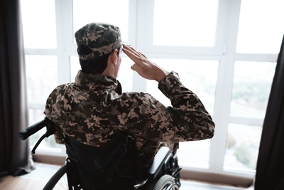 The disabled in military uniform sits in a wheelchair. He looks out the window and salutes. In front of him is a large panoramic window. He is in his modern apartment.
