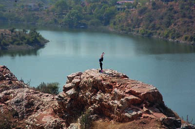Girl stretches and takes in the relaxing view of the lake from Bahubali Hill in Udaipur, Rajasthan, India