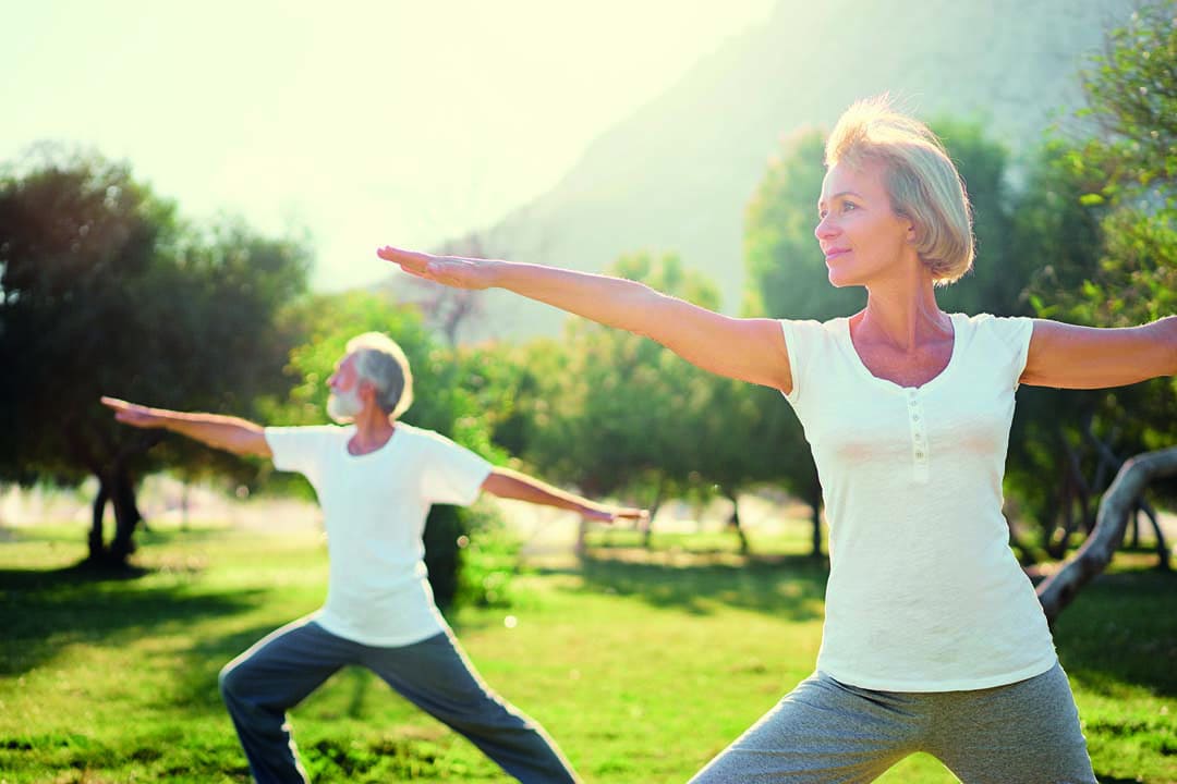 Yoga at park. Senior family couple exercising outdoors. Concept of healthy lifestyle.