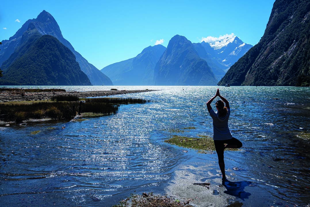 Athletic female practicing yoga outdoors, Milford Sound, New Zealand