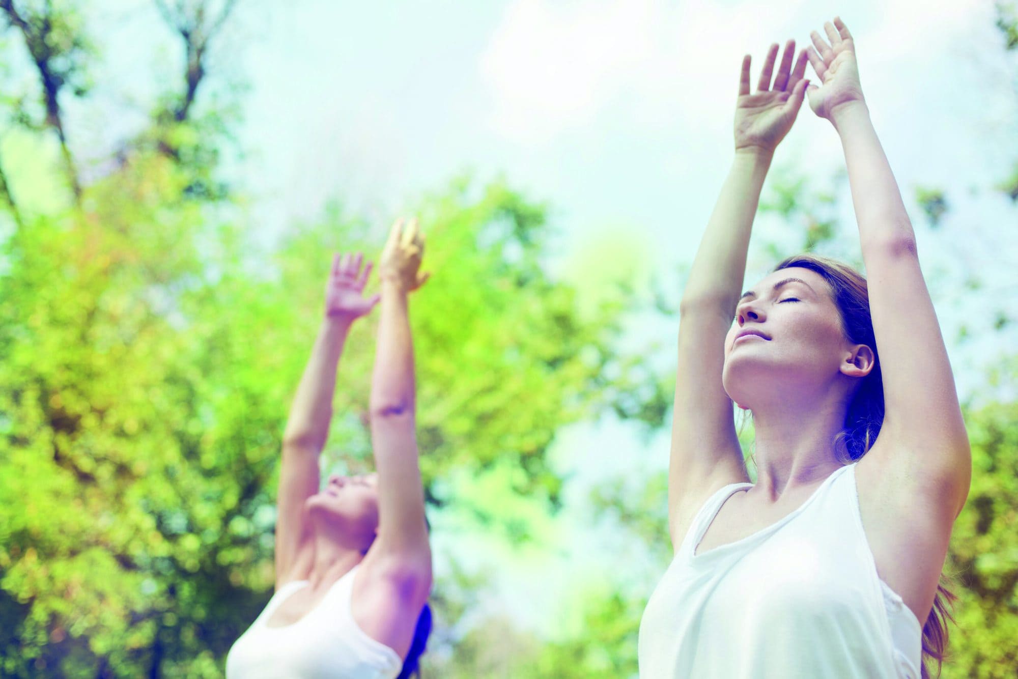 Two beautiful young women doing yoga class in nature.