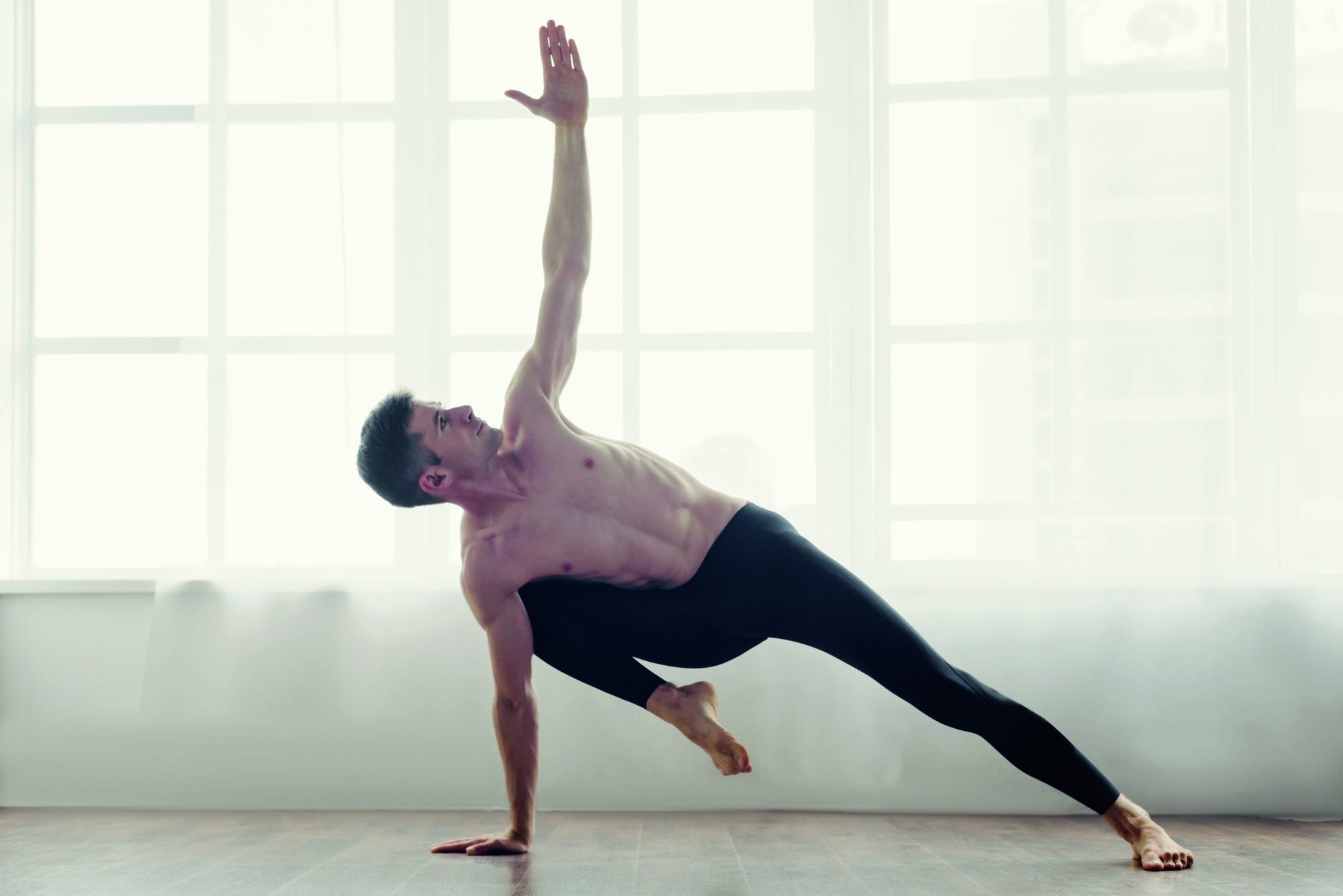 Young man practicing side plank yoga pose