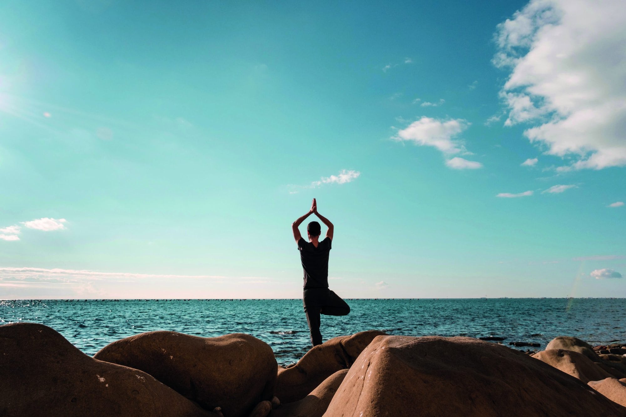 Attractive young man practicing yoga meditation and breathwork outdoors by the sea