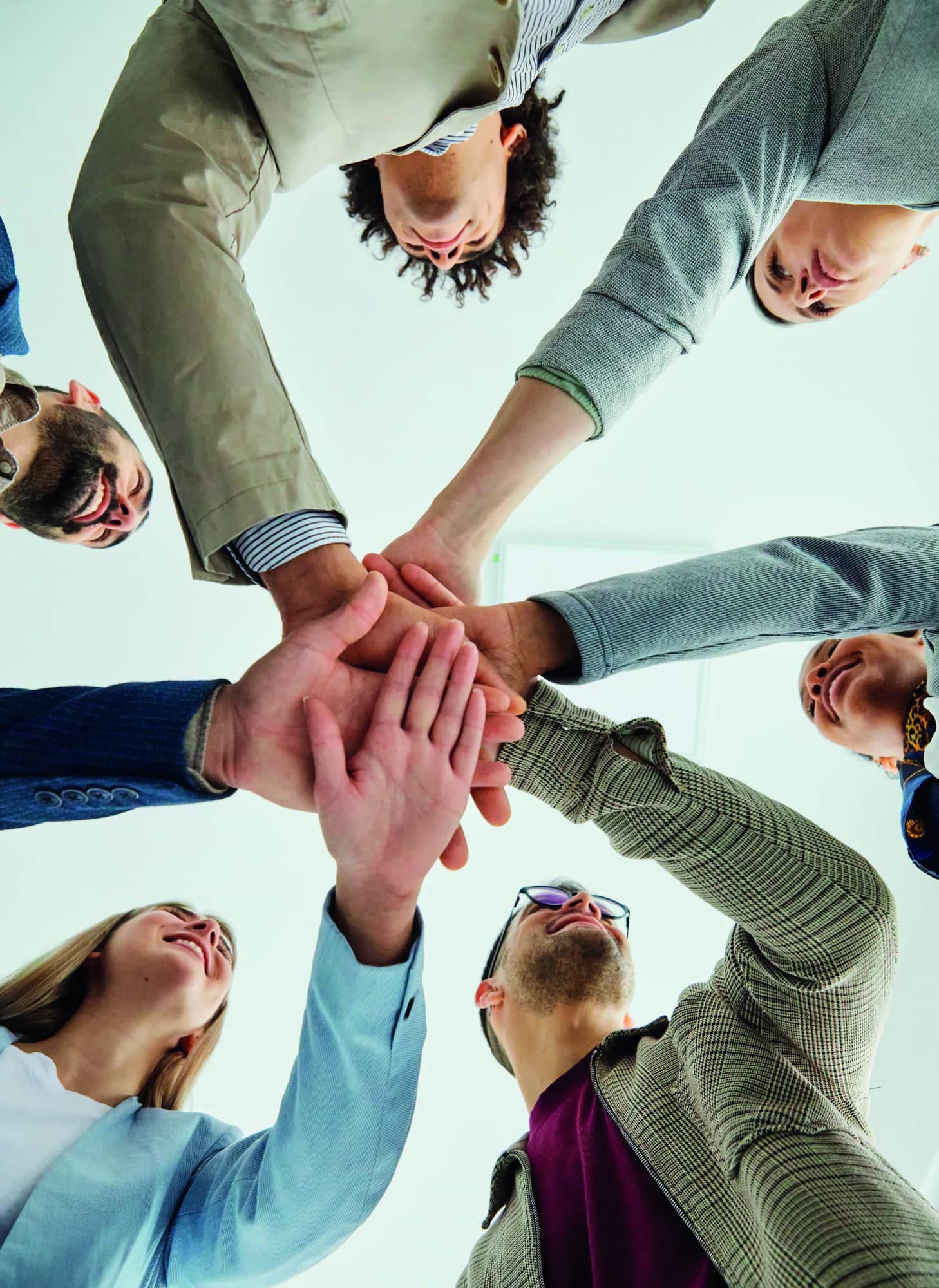 Portrait of a group of young and senior business people holding hands together in the office. Teamwork and success concept