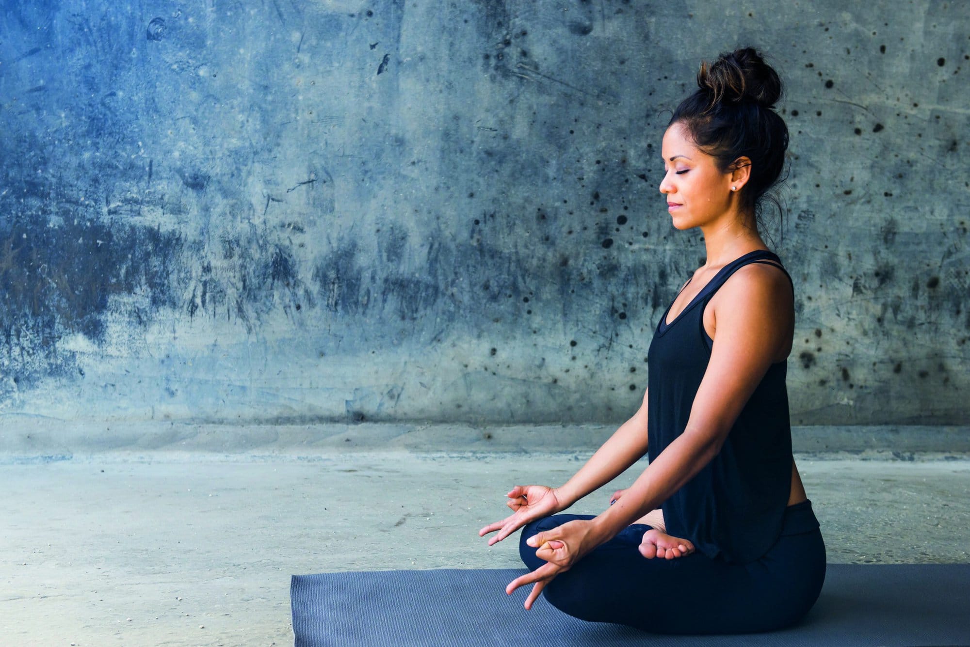 Latin woman practicing meditation against a urban background