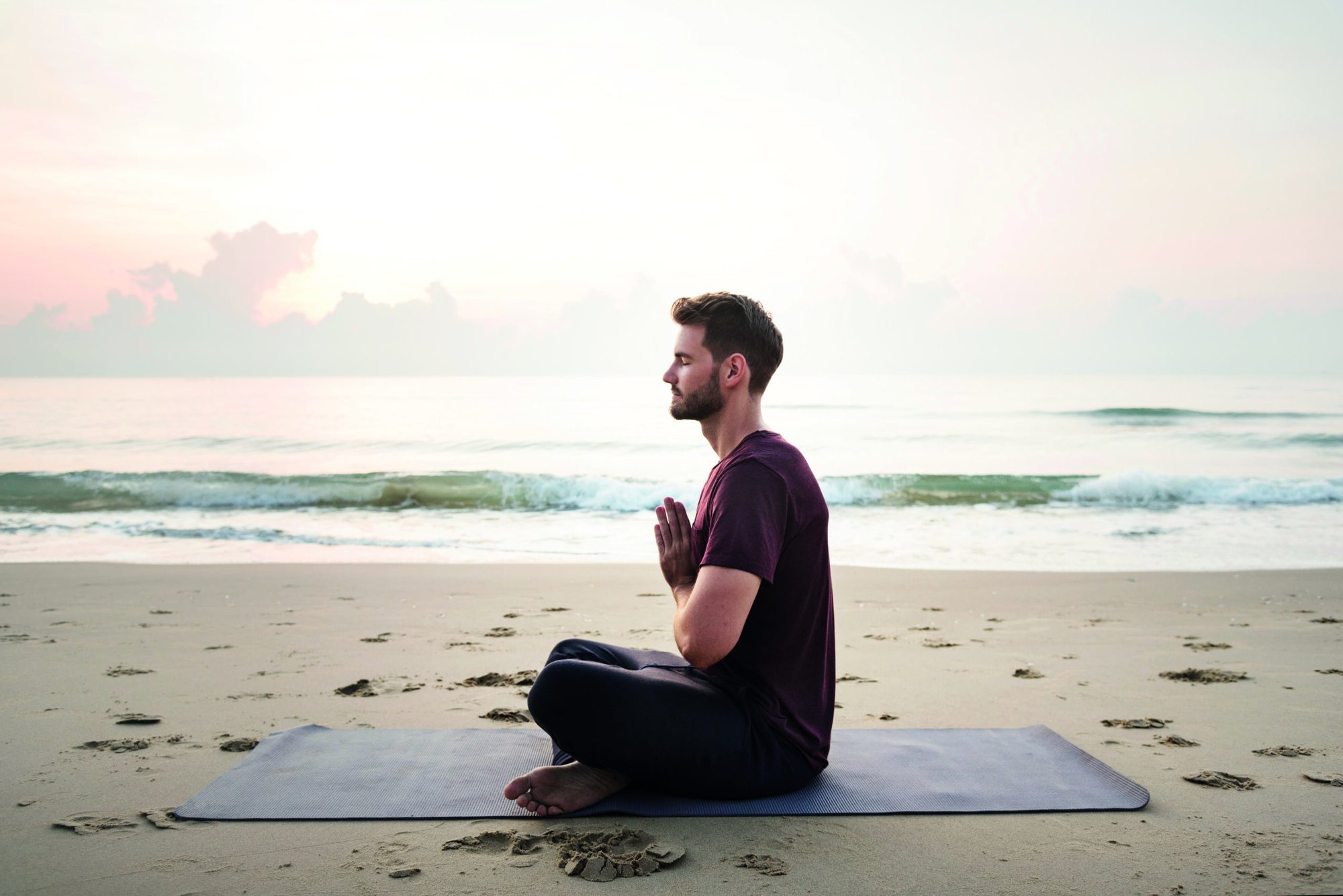 Man practicing yoga on the beach