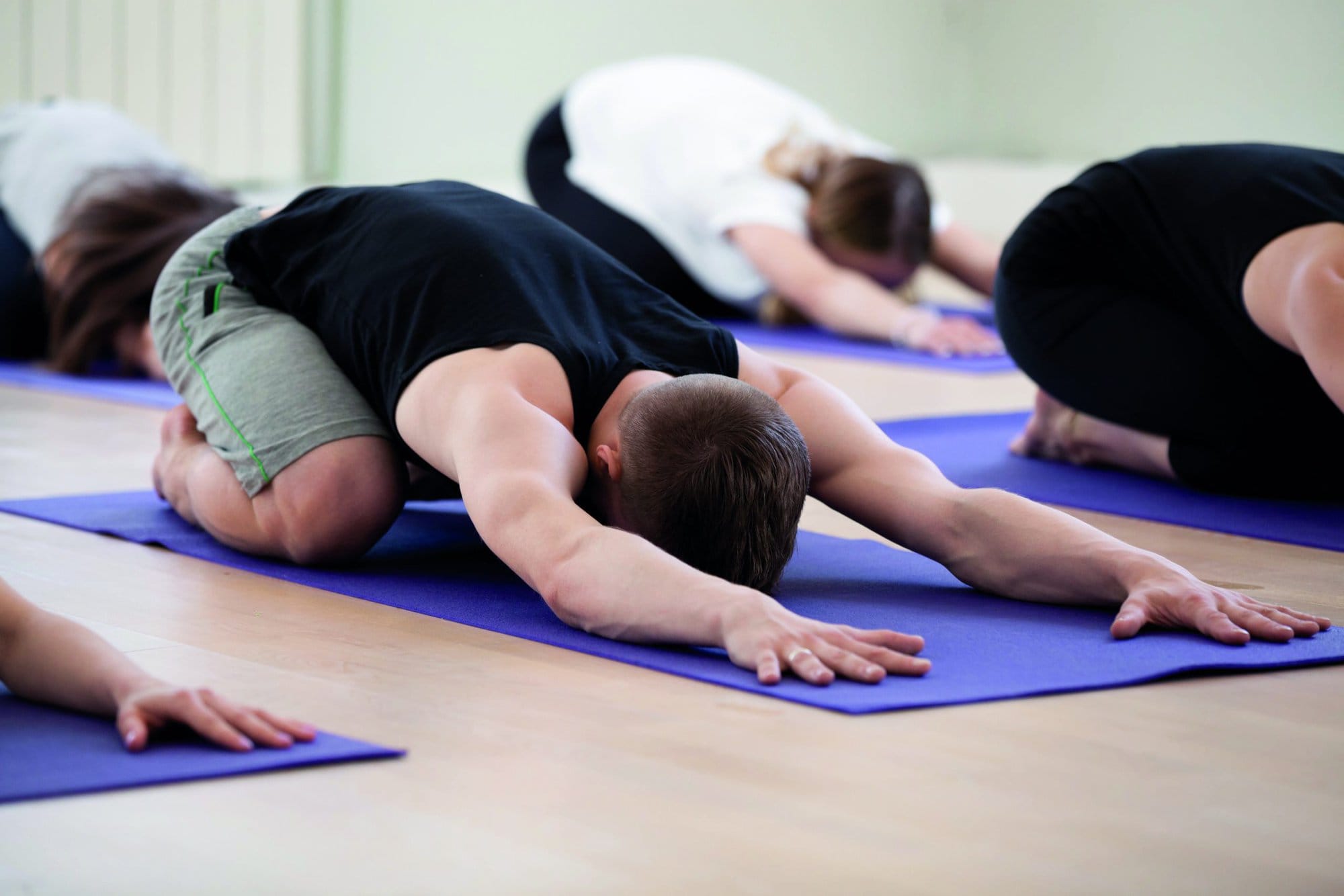 Group of young sporty people practicing yoga lesson, doing Child exercise, resting in Balasana pose, working out, indoor studio session close up, students training in club. Healthy wellbeing lifestyle