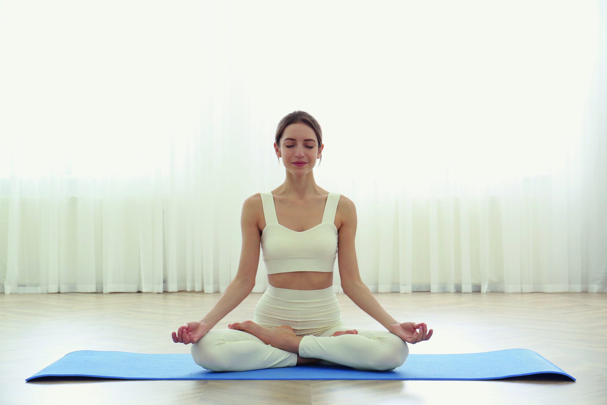 Young woman practicing lotus asana in yoga studio. Padmasana pose