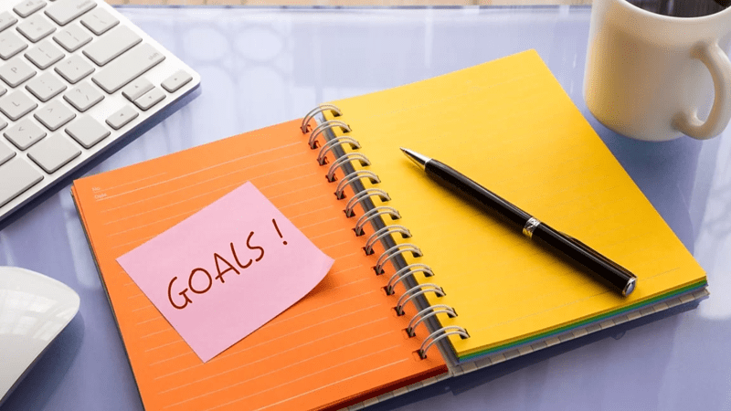Goals word on note pad stick on blank colorful paper notebook at workspace, year resolution concepts