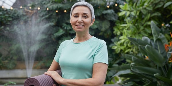 Woman Smiling While Holding a Yoga Mat