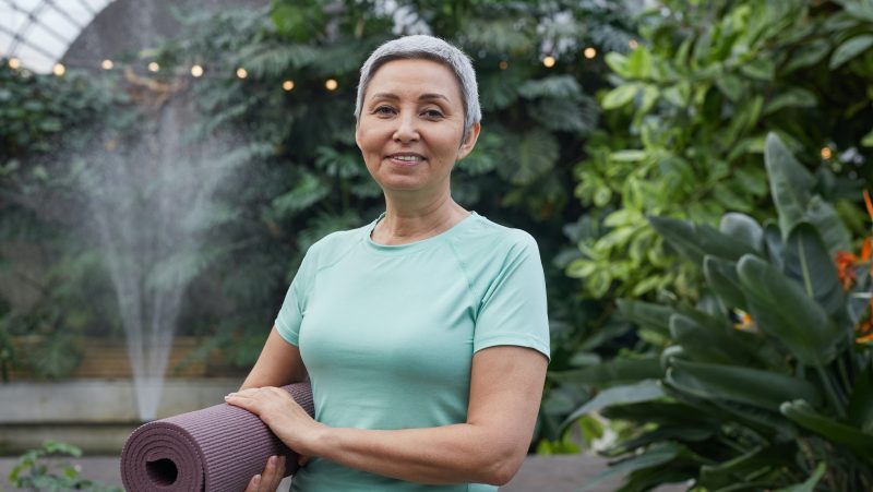 Woman Smiling While Holding a Yoga Mat