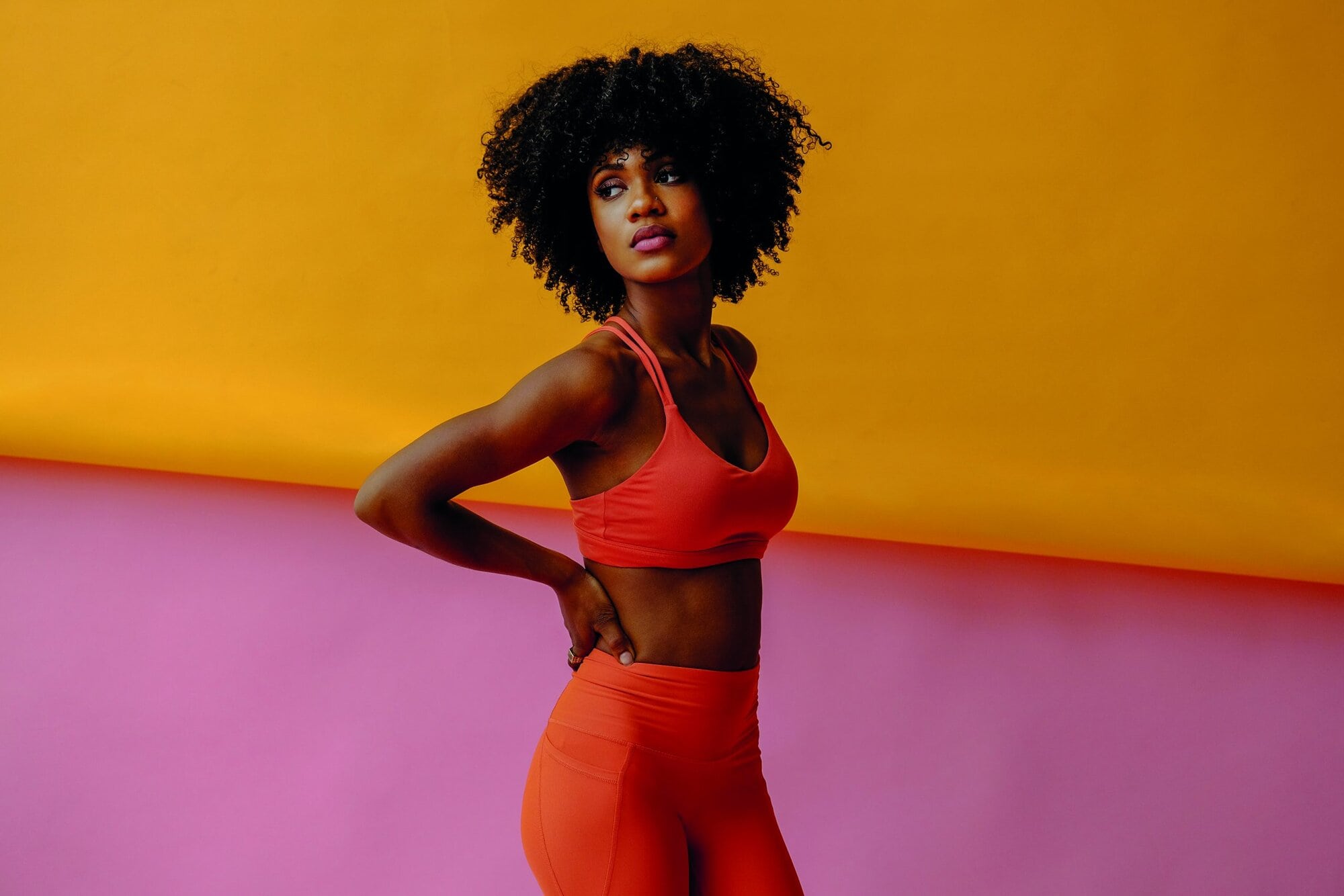 serious young adult woman in sports outfit looking aside and posing in studio