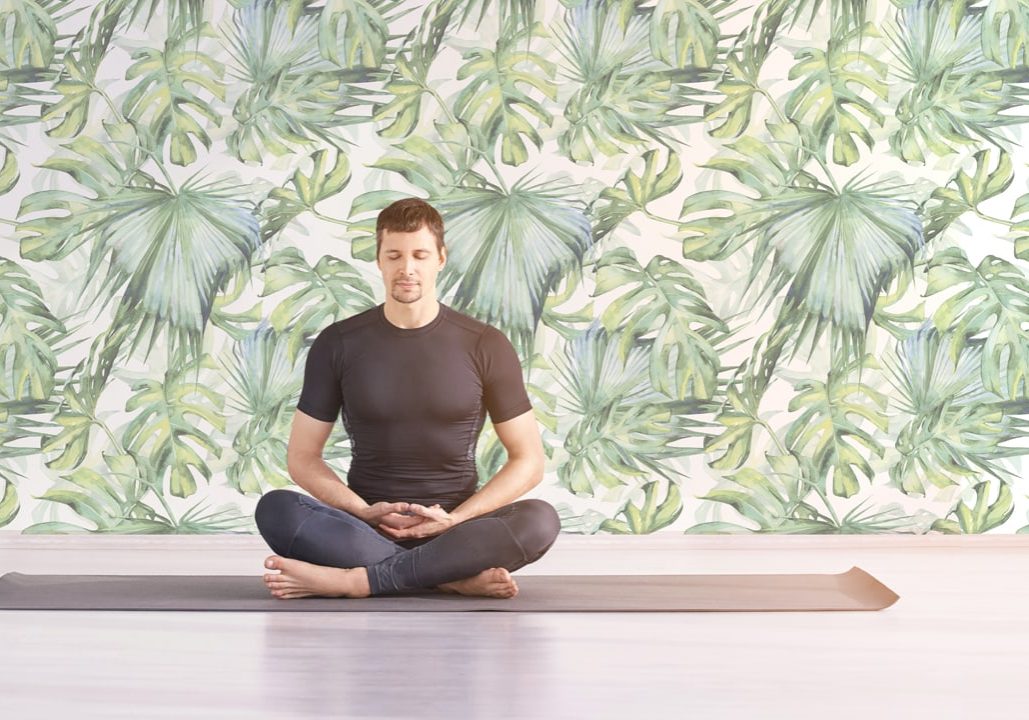 Man sitting at lotus yoga pose. Home morning routine. Teacher fitness studio. Asana class. Online exercise. Relaxation indoor. Male prayer in house room. Light background. Close eyes