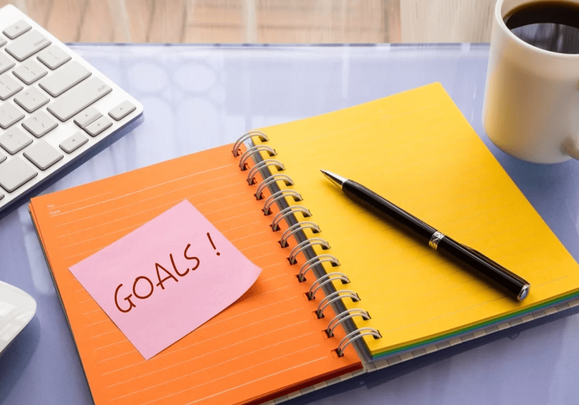 Goals word on note pad stick on blank colorful paper notebook at workspace, year resolution concepts