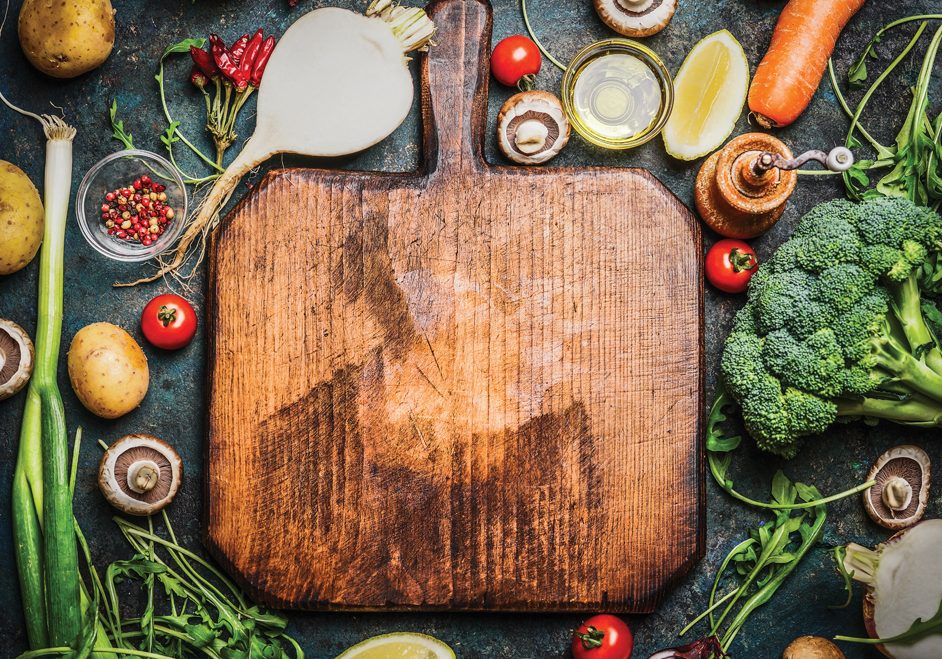 Fresh vegetables and  ingredients for cooking around vintage cutting board on rustic background, top view, place for text.  Vegan food , vegetarian and healthily cooking concept.