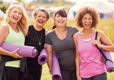 Portrait Of Mature Female Friends On Outdoor Yoga Retreat Walking Along Path Through Campsite