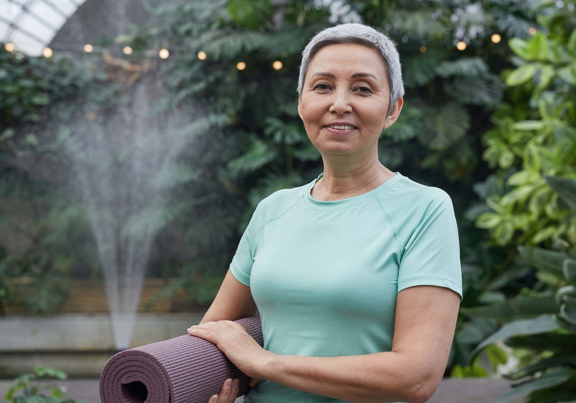 Woman Smiling While Holding a Yoga Mat
