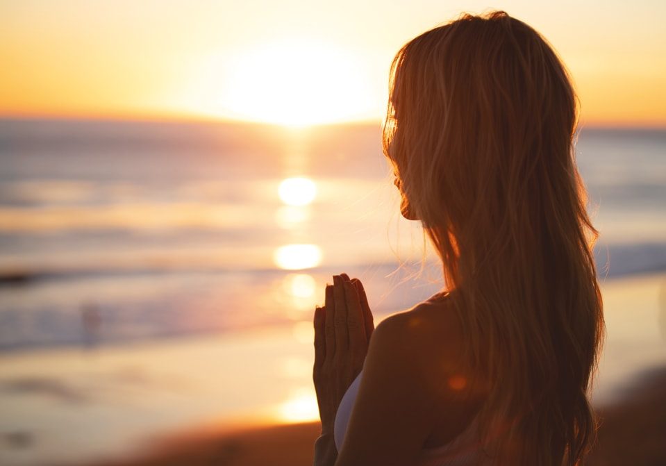 girl meditating at sunset on beach