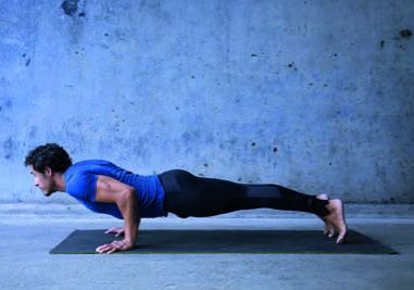 Young man practicing yoga. Basic yoga pose: chaturanga dandasana.